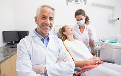 Dentist with patient and staff in background