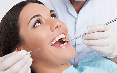 A woman sitting in a dental chair having her teeth cleaned