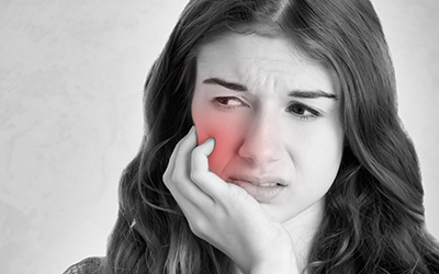 A woman holding the side of her mouth in pain