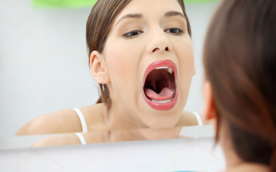 A young woman with mouth open checking throat