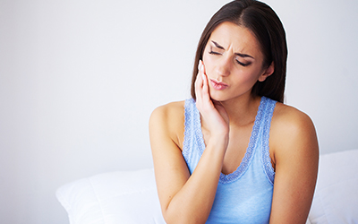 A woman holding her jaw in pain