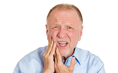 An older male holding the side of his mouth in pain