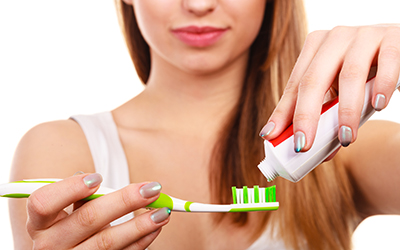 Woman applying toothpaste to toothbrush