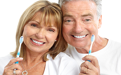 An elderly couple holding toothbrushes