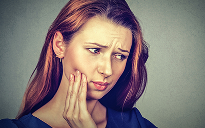 A woman holding her jaw in pain