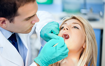 A dentist working on a female's teeth